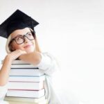 61639542-picture-of-happy-student-in-graduation-cap-with-stack-of-books